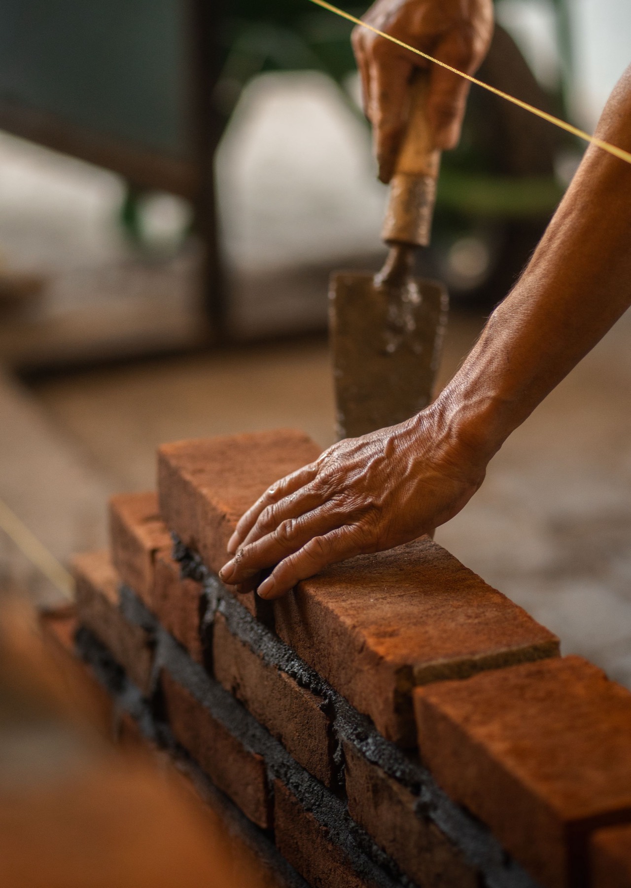 A bricklayer's hand bedding a brick into mortar along a line