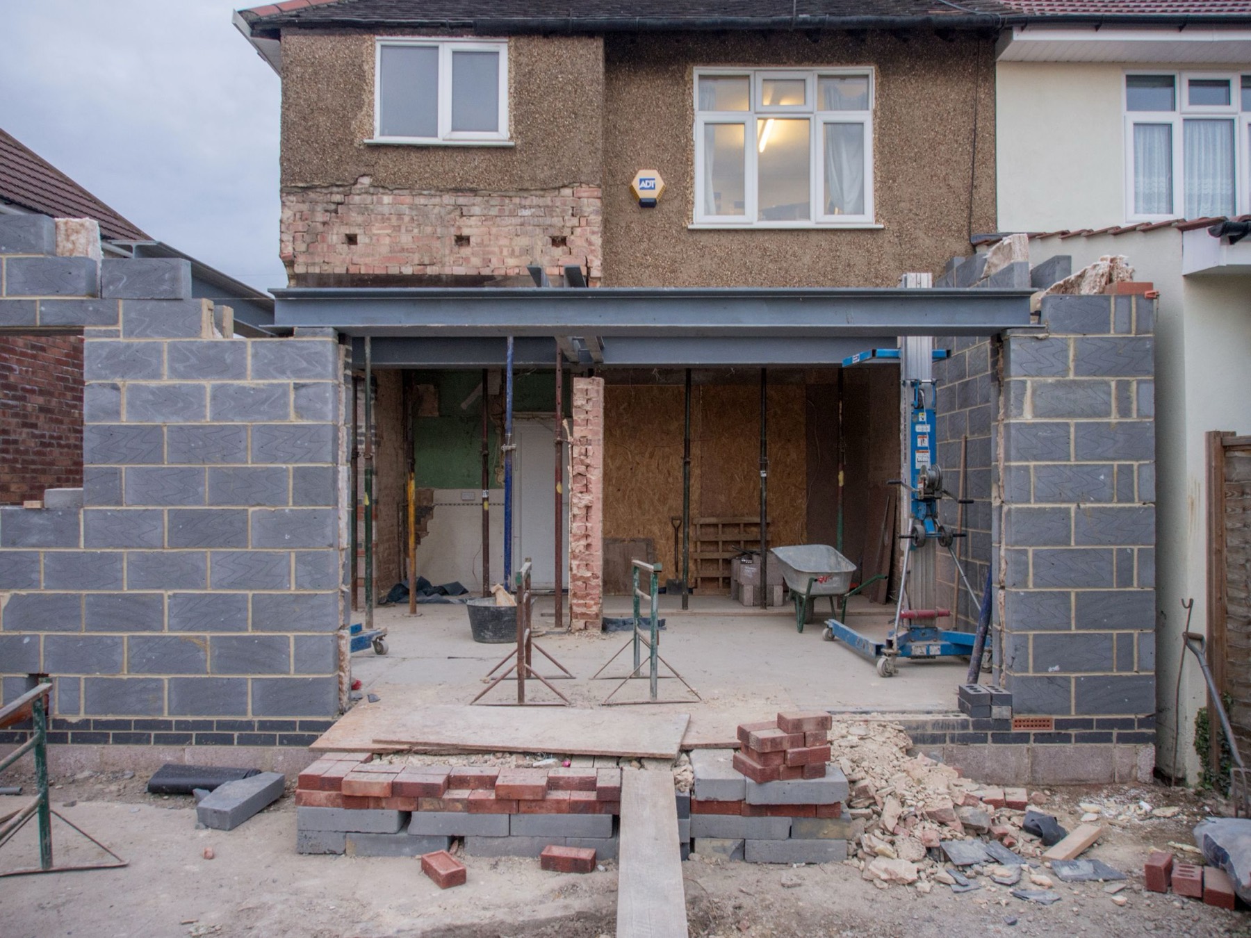 A two-storey rear extension part-way through construction — blockwork, a steel beam and a new opening into the original house