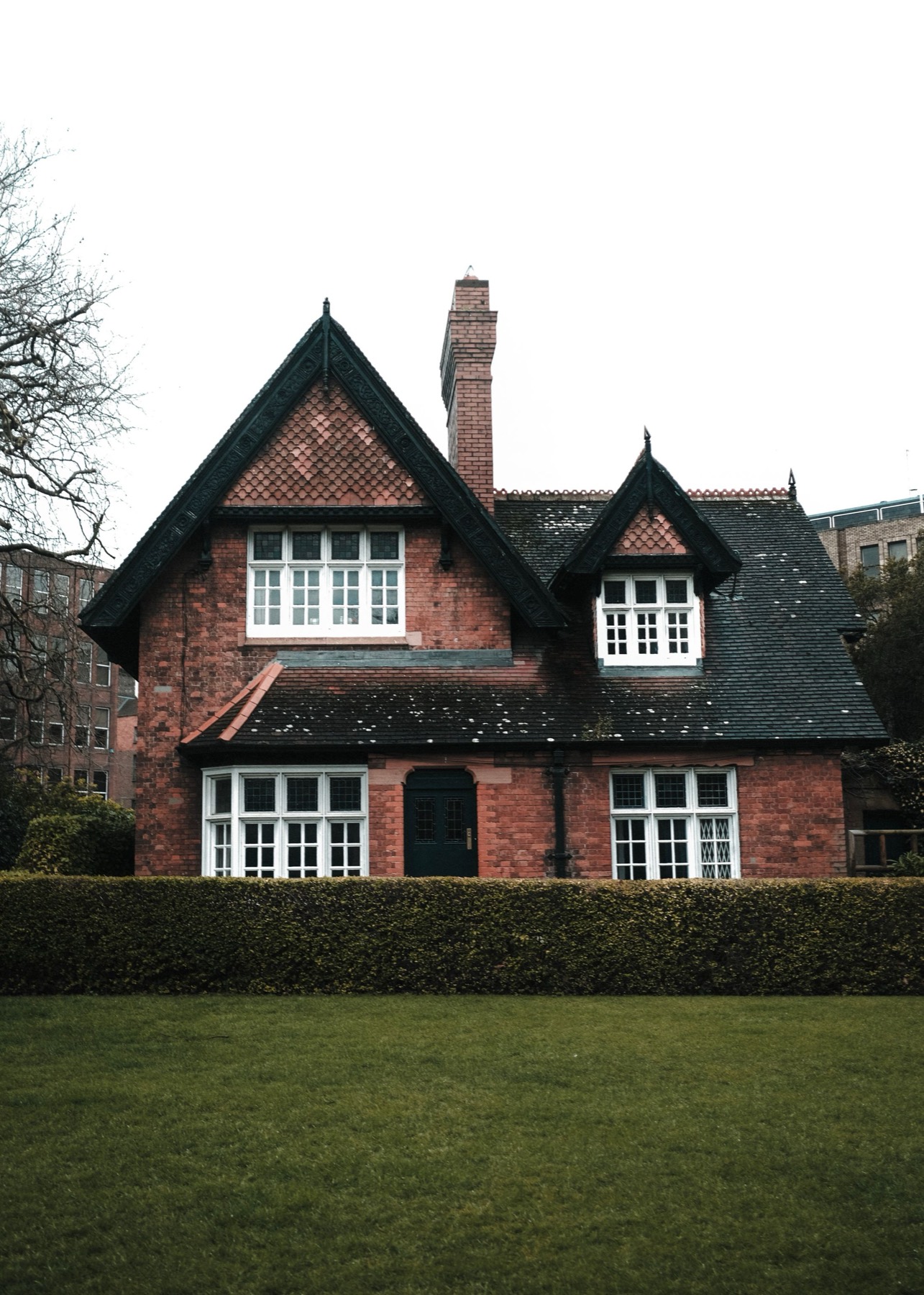 A traditional red-brick house behind a clipped hedge in an English village